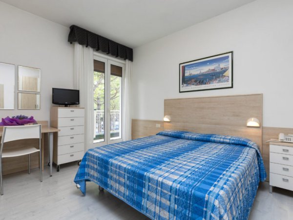 Camera da letto con letto matrimoniale, coperte blu, TV e scrivania.